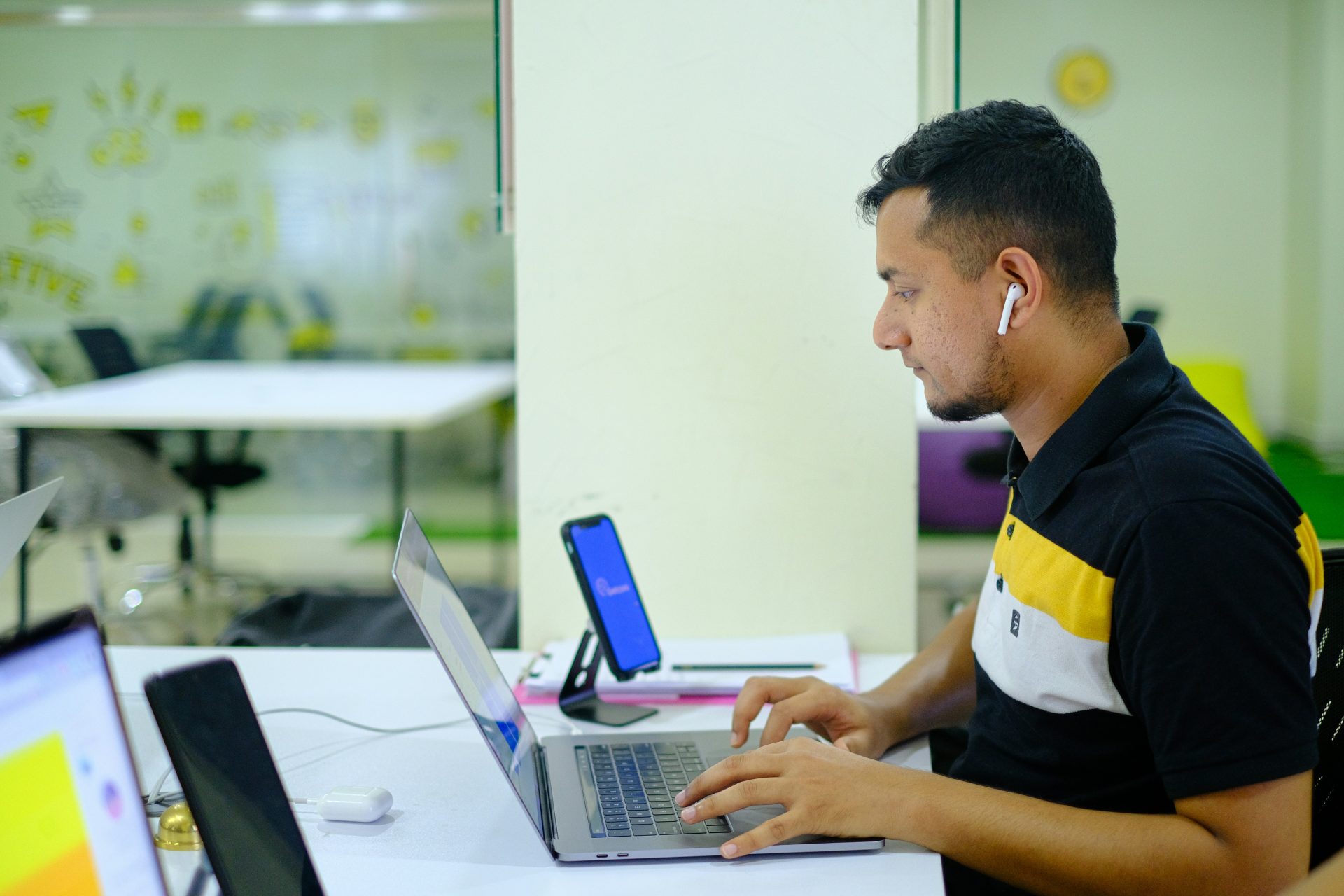 Hombre con polo negro y amarillo usando un MacBook Pro